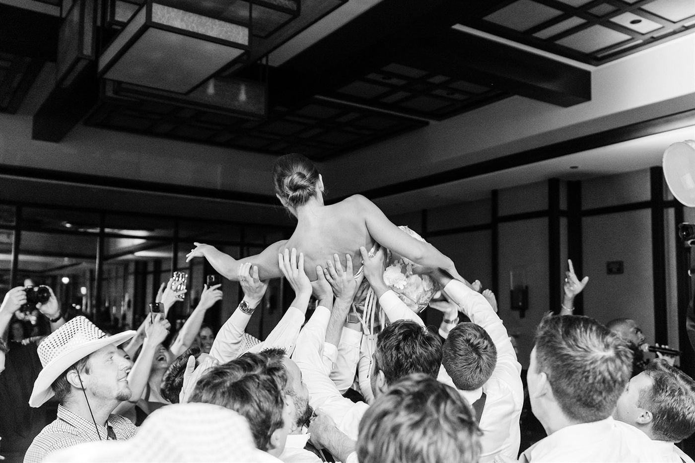 A bride lifted above a cheering crowd on the dance floor at a reception